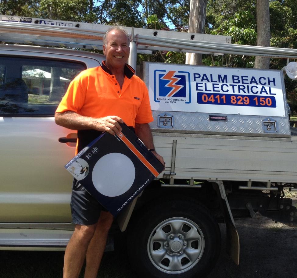 Peter next to his work car holding a ceiling light 40 W before installing for a client. 